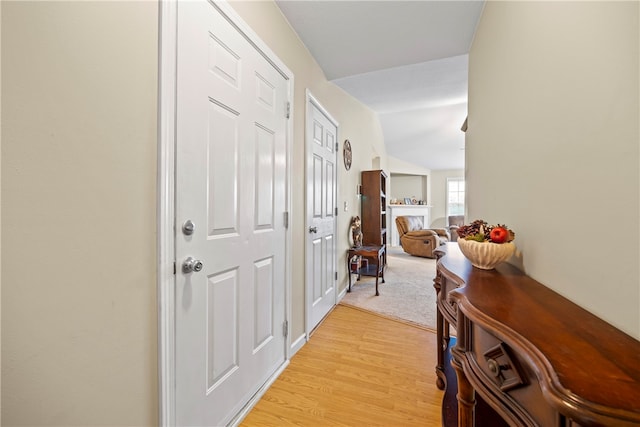 corridor with vaulted ceiling and light wood-style floors