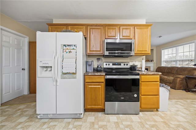 kitchen with open floor plan, appliances with stainless steel finishes, and brown cabinets