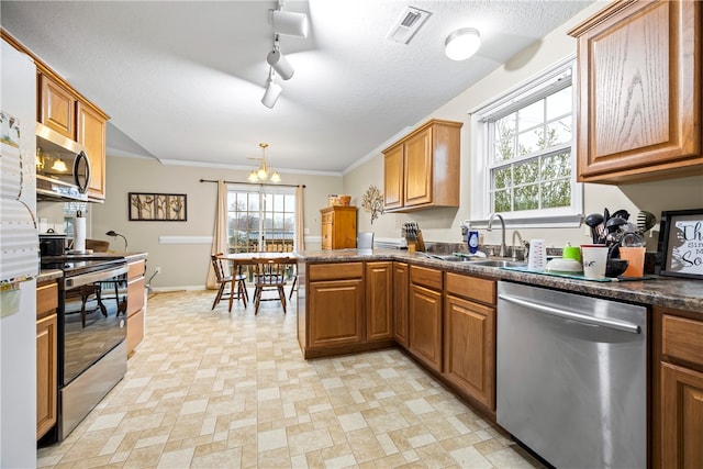 kitchen featuring stainless steel appliances, brown cabinets, dark countertops, and visible vents