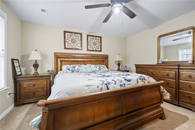 bedroom featuring visible vents, light colored carpet, baseboards, and ceiling fan