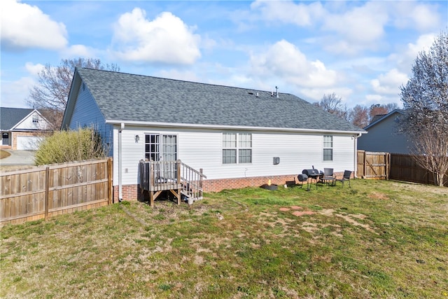 back of house with a lawn, a fenced backyard, and a shingled roof