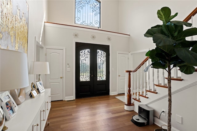 entryway featuring baseboards, stairs, french doors, a high ceiling, and wood finished floors