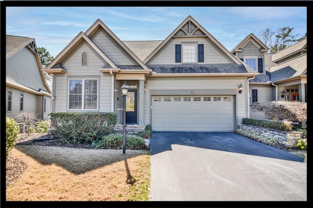 craftsman-style home featuring an attached garage, roof with shingles, and driveway