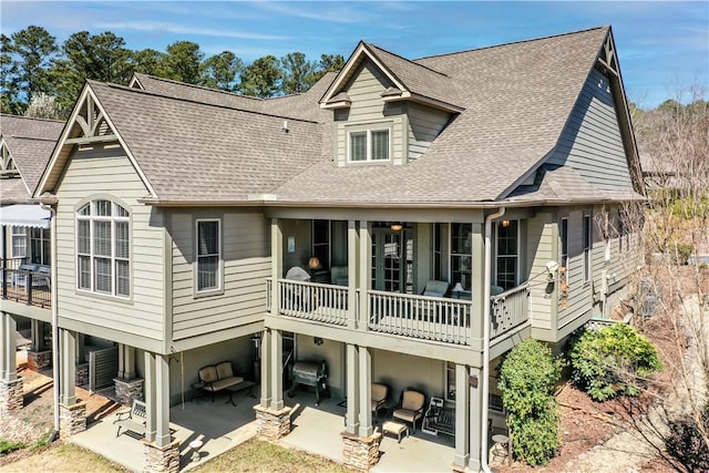 rear view of property featuring a carport, roof with shingles, and a patio area