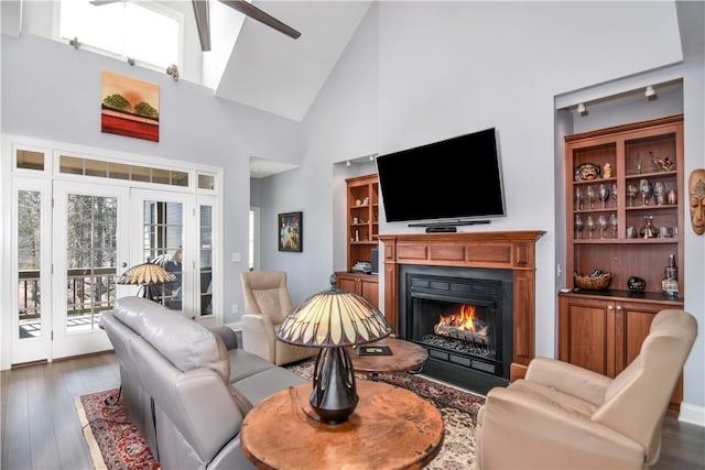 living room with high vaulted ceiling, wood finished floors, and a lit fireplace