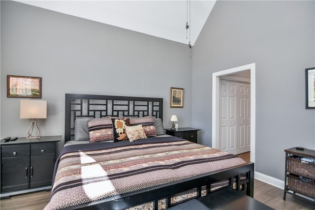 bedroom with baseboards, high vaulted ceiling, and wood finished floors