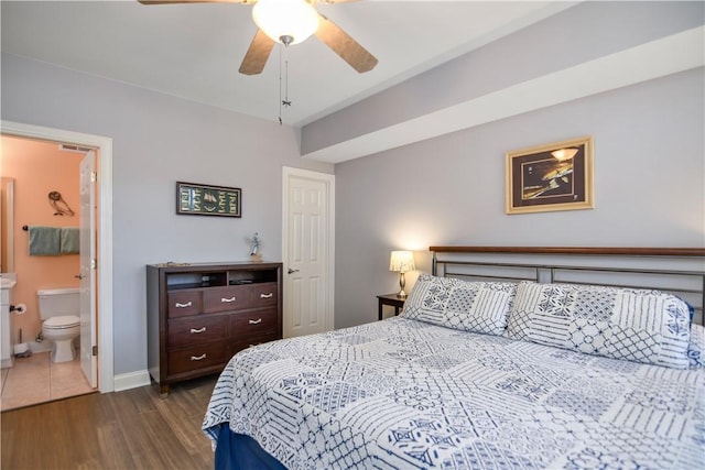 bedroom with dark wood finished floors, connected bathroom, a ceiling fan, and baseboards