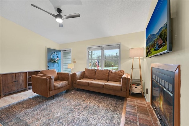 living area featuring a glass covered fireplace and a ceiling fan