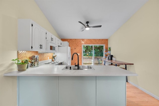 kitchen with a sink, white appliances, a peninsula, and light countertops