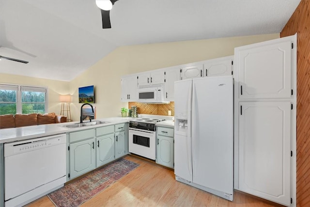 kitchen featuring light wood finished floors, ceiling fan, vaulted ceiling, white appliances, and a sink