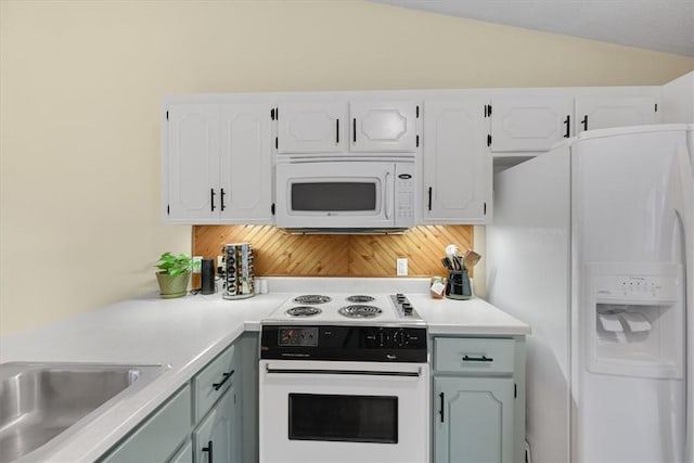 kitchen featuring white appliances, lofted ceiling, a sink, light countertops, and white cabinetry