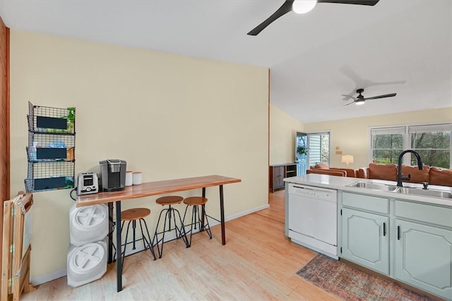 kitchen with light wood-style flooring, white dishwasher, ceiling fan, a sink, and vaulted ceiling