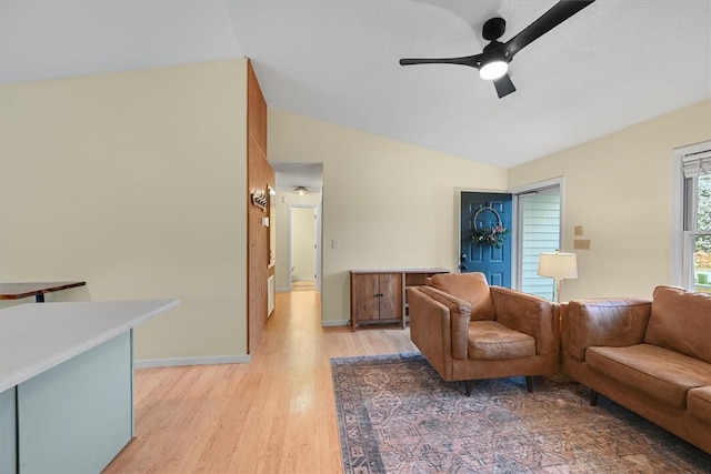 living room with a ceiling fan, lofted ceiling, light wood-style floors, and baseboards