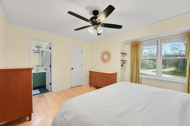 bedroom with light wood finished floors, ceiling fan, baseboards, ensuite bathroom, and a sink