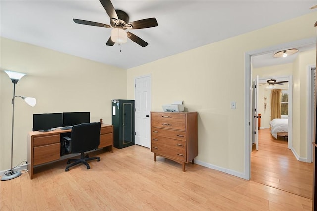 office featuring a ceiling fan, baseboards, and light wood finished floors