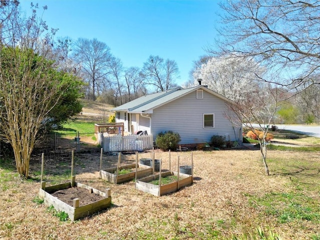 view of home's exterior featuring a lawn, a vegetable garden, and fence