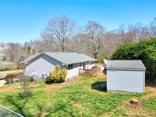 view of yard featuring an outbuilding, a storage unit, fence, and a wooden deck