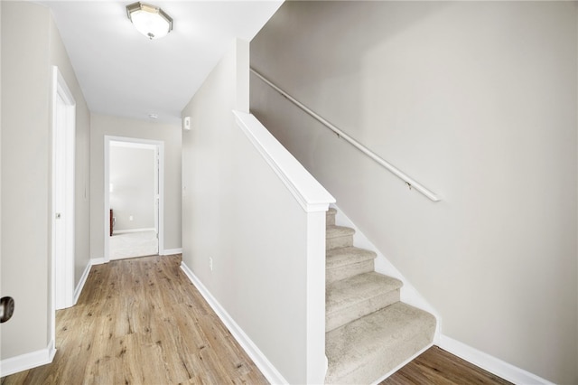 staircase with baseboards and wood finished floors