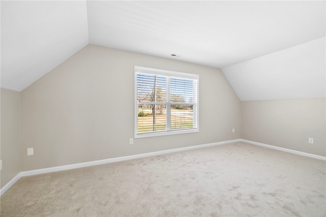 additional living space with lofted ceiling, baseboards, visible vents, and light carpet