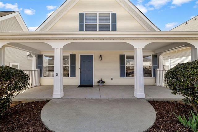 view of exterior entry with a porch and a gambrel roof