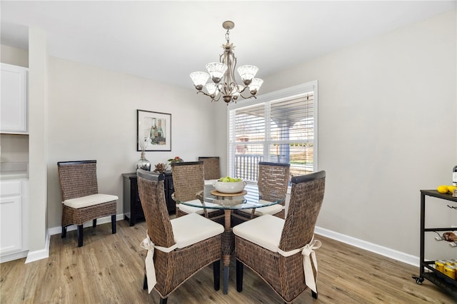 dining space with a chandelier, light wood finished floors, and baseboards