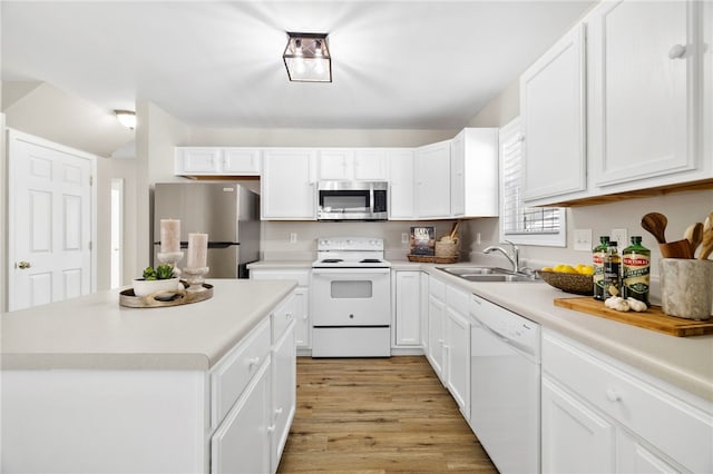 kitchen with light wood finished floors, light countertops, appliances with stainless steel finishes, white cabinets, and a sink