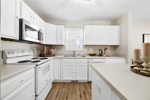 kitchen featuring light wood-style flooring, a sink, white appliances, white cabinets, and light countertops