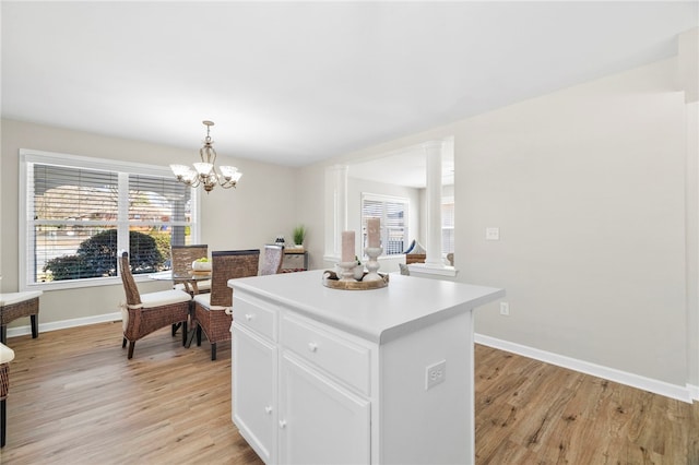 kitchen featuring a kitchen island, decorative columns, light countertops, light wood-style floors, and white cabinetry