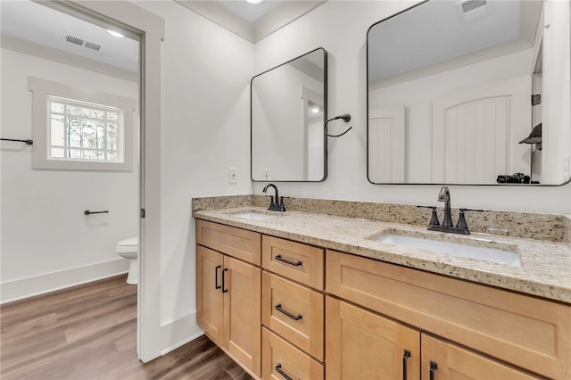 bathroom with toilet, wood finished floors, visible vents, and a sink