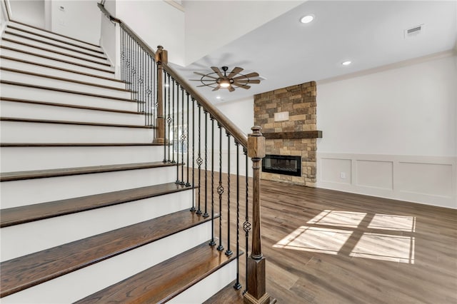 staircase with visible vents, recessed lighting, a fireplace, wood finished floors, and a decorative wall