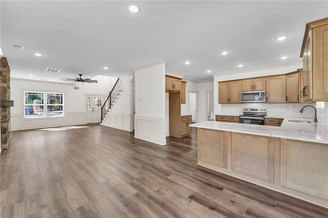 kitchen with light stone counters, dark wood-style floors, visible vents, a sink, and appliances with stainless steel finishes