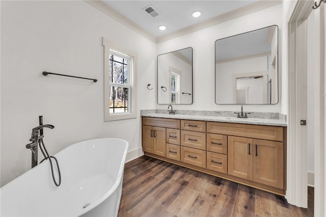 full bath with double vanity, visible vents, wood finished floors, and a sink