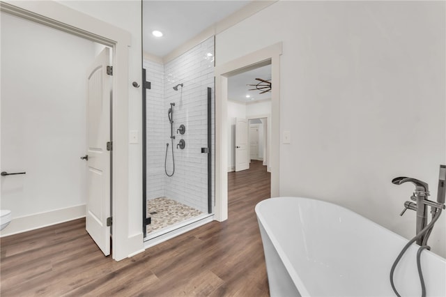 full bathroom featuring a freestanding tub, a stall shower, baseboards, and wood finished floors