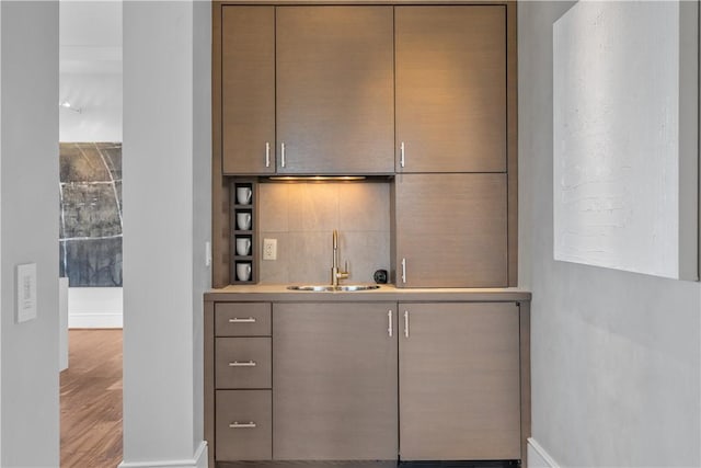 bar with a sink, indoor wet bar, baseboards, and wood finished floors