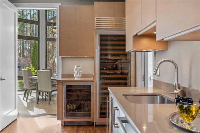 kitchen featuring modern cabinets, light countertops, beverage cooler, and a sink