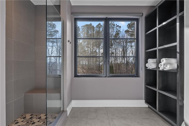 interior space featuring tile patterned floors, baseboards, and tiled shower