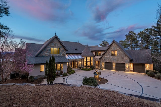 view of front of home featuring a standing seam roof, an attached garage, concrete driveway, stone siding, and metal roof