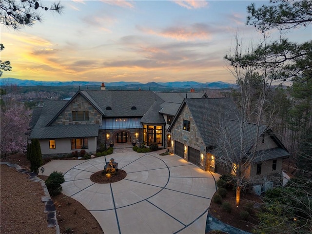 view of front of home featuring a mountain view, stone siding, and driveway