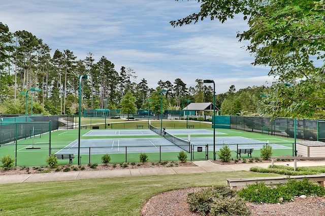 view of tennis court with a yard and fence