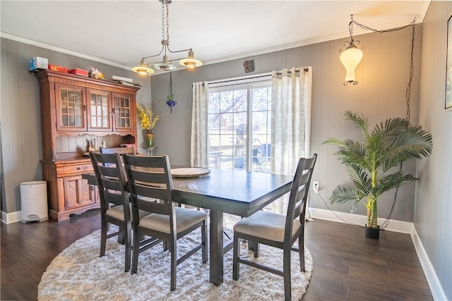 dining space featuring dark wood-style floors, crown molding, and baseboards