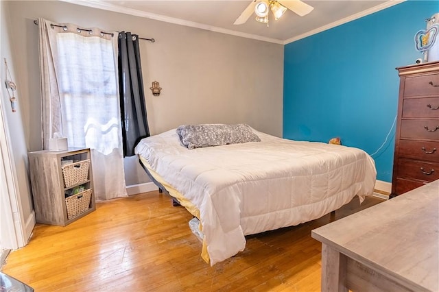 bedroom with crown molding, light wood-style flooring, a ceiling fan, and baseboards