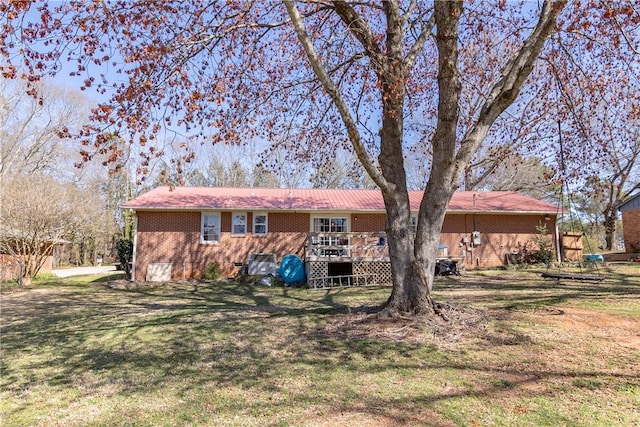 rear view of house featuring a wooden deck, brick siding, and a lawn