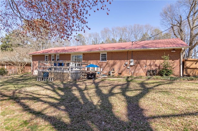 rear view of property featuring brick siding, crawl space, a lawn, and a deck