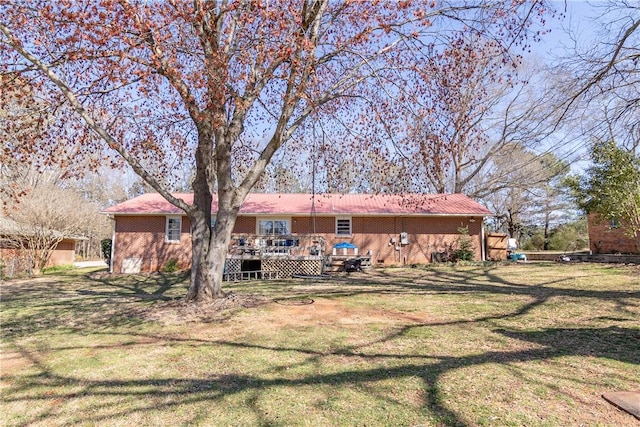 back of property with a deck, a yard, and brick siding