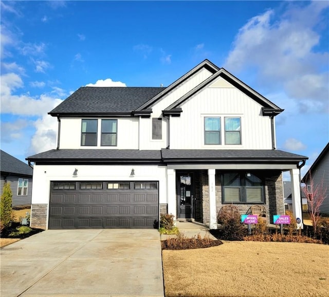 modern farmhouse with board and batten siding, an attached garage, stone siding, and driveway