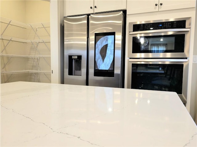 kitchen with light stone counters, stainless steel appliances, and white cabinetry