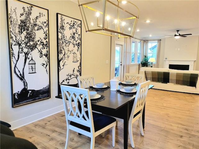 dining room with a ceiling fan, baseboards, recessed lighting, a fireplace, and light wood-type flooring