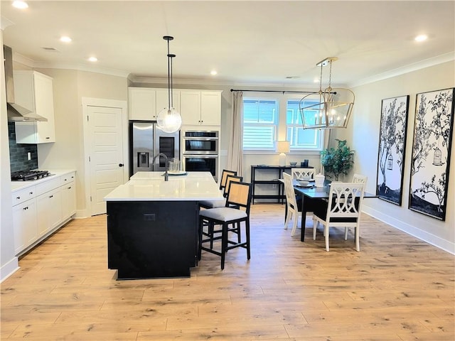 kitchen with backsplash, stainless steel appliances, light wood-style floors, and ornamental molding