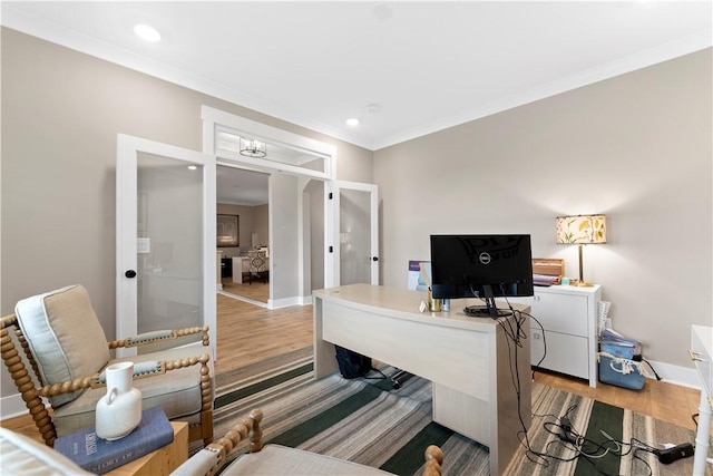 office area with light wood-style floors, baseboards, and ornamental molding