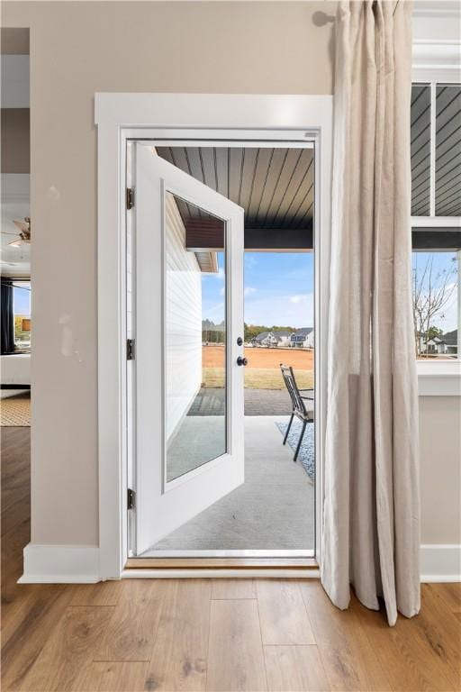 doorway featuring baseboards and wood finished floors